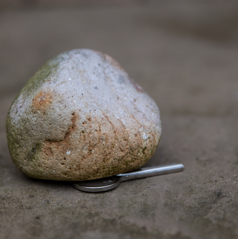 A picture of a key badly hidden under a small rock.